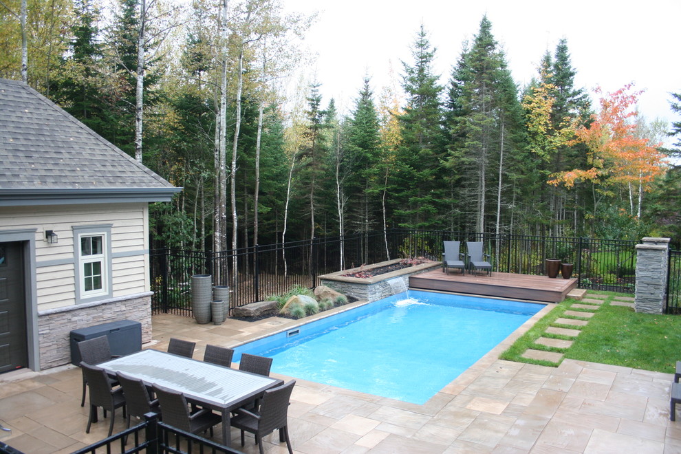 This is an example of a mid-sized traditional backyard rectangular pool in Other with concrete pavers.