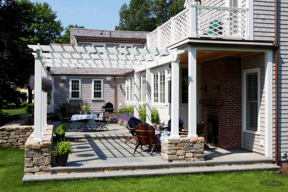 Photo of a large country backyard patio in Boston with an outdoor kitchen, natural stone pavers and a pergola.