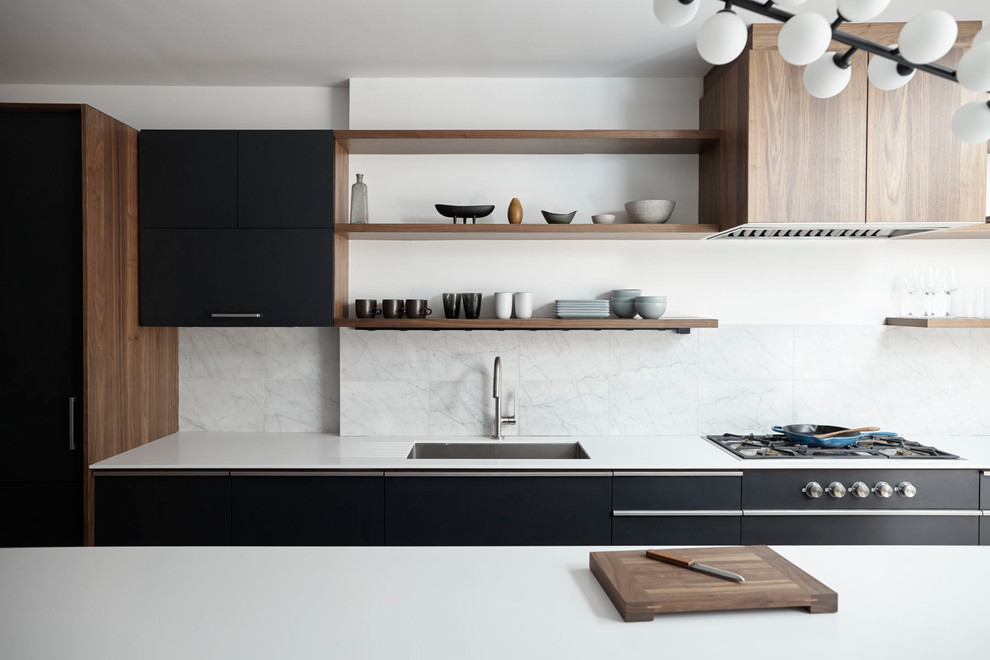 Design ideas for a mid-sized modern single-wall eat-in kitchen in New York with an undermount sink, flat-panel cabinets, black cabinets, quartzite benchtops, white splashback, travertine splashback, panelled appliances, light hardwood floors, with island and beige floor.