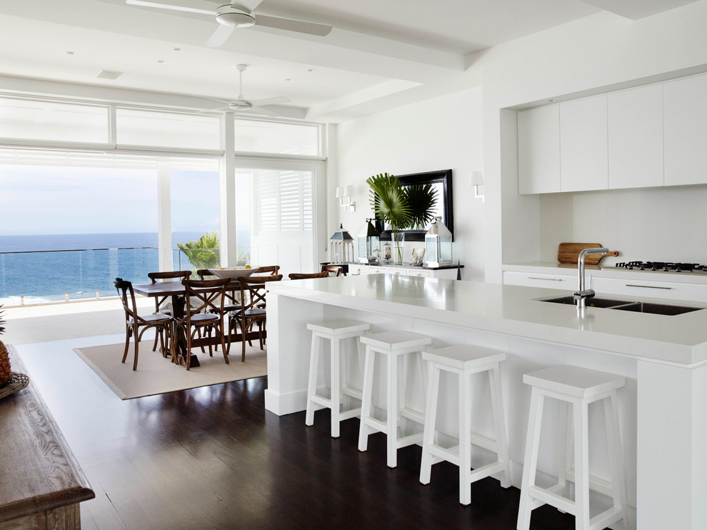 Photo of a mid-sized beach style eat-in kitchen in Sydney with flat-panel cabinets, white cabinets, quartz benchtops, dark hardwood floors and white benchtop.