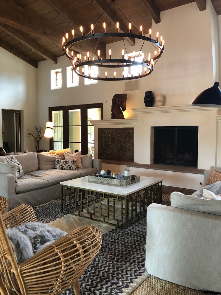 Inspiration for a transitional living room in Santa Barbara with beige walls, a standard fireplace, a plaster fireplace surround and brown floor.