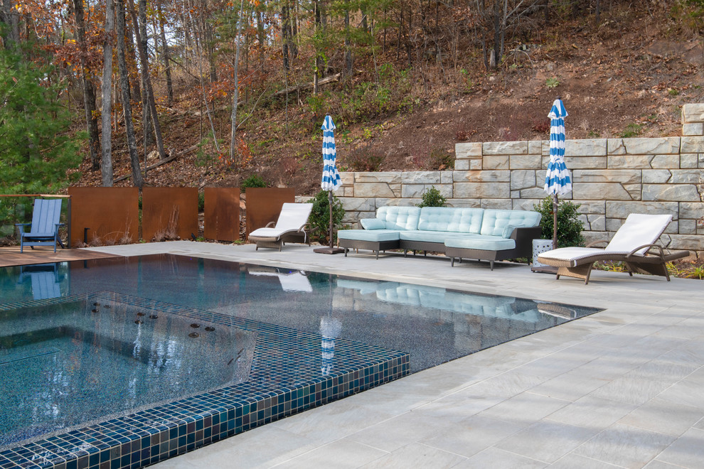 Photo of a large midcentury backyard rectangular infinity pool in Other with a hot tub.