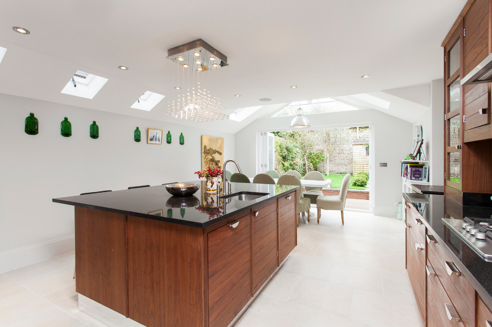 This is an example of a contemporary kitchen in London with glass-front cabinets and dark wood cabinets.