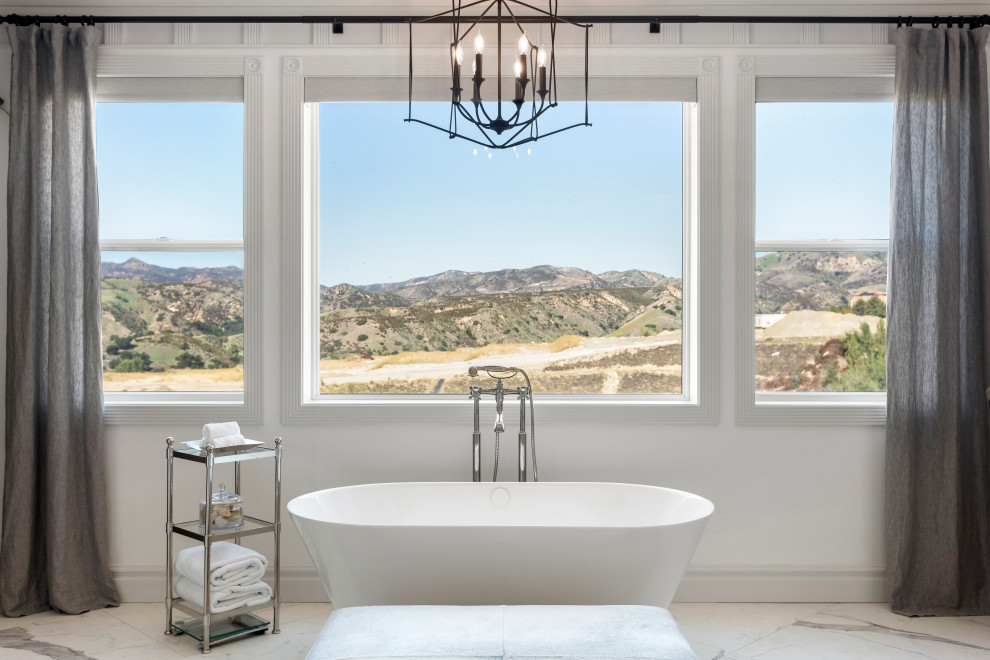 This is an example of a large traditional master bathroom in Los Angeles with shaker cabinets, white cabinets, a freestanding tub, a one-piece toilet, white tile, porcelain tile, white walls, porcelain floors, a drop-in sink, engineered quartz benchtops, white floor, a hinged shower door, grey benchtops, a shower seat, a double vanity, a built-in vanity and wallpaper.