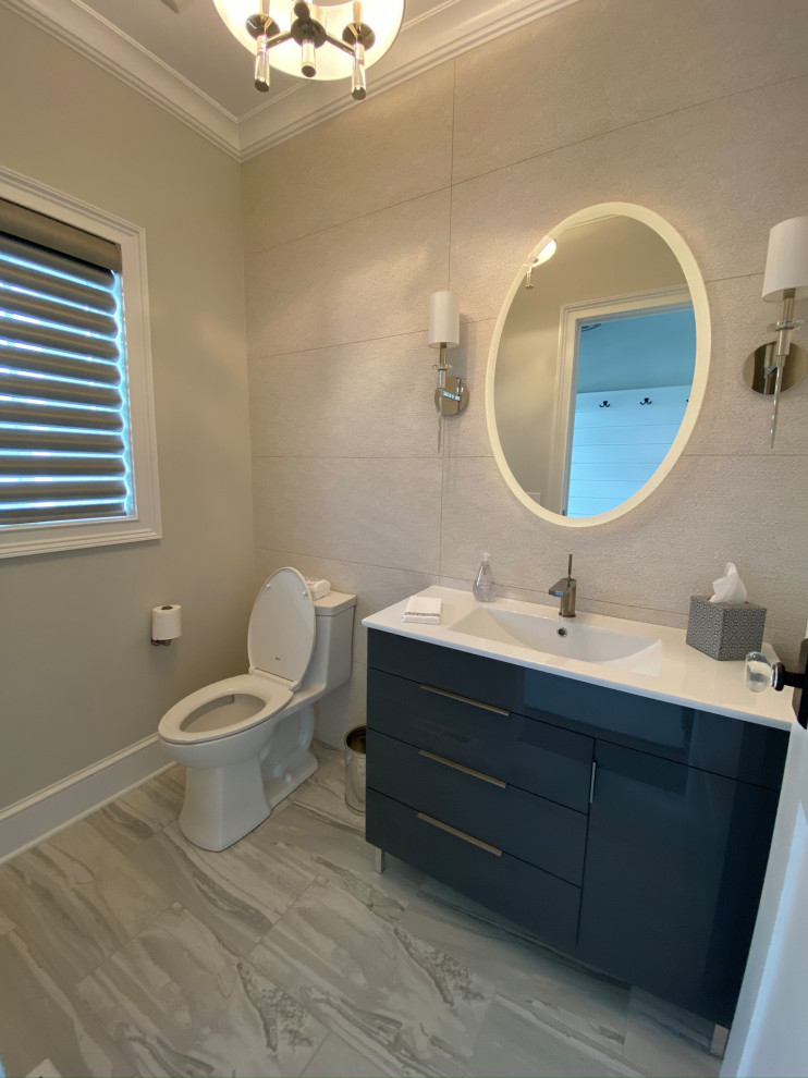 Beach style powder room in New York with flat-panel cabinets, grey cabinets, a one-piece toilet, white tile, porcelain tile, grey walls, ceramic floors, an undermount sink, grey floor, white benchtops and a freestanding vanity.