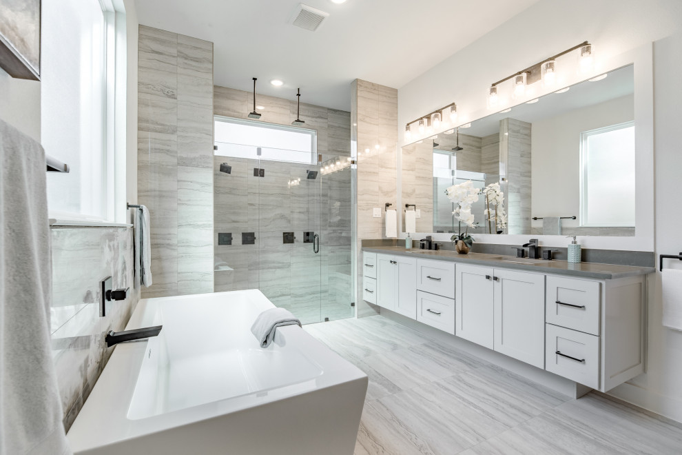 Expansive contemporary master bathroom in Dallas with shaker cabinets, grey cabinets, a freestanding tub, an alcove shower, gray tile, white walls, an undermount sink, grey floor, a hinged shower door and grey benchtops.