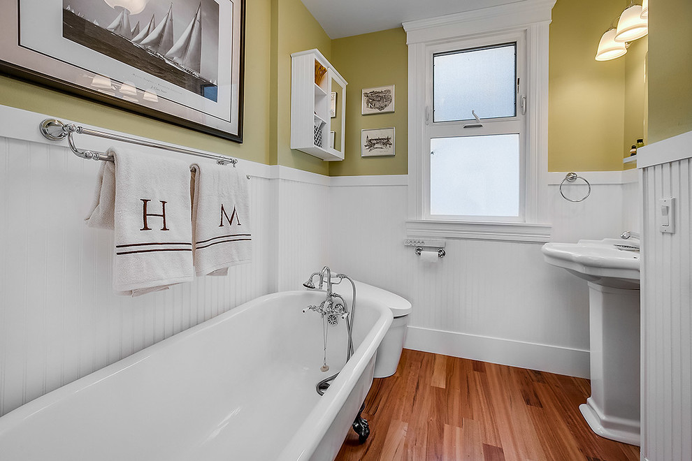 Design ideas for a contemporary 3/4 bathroom in Seattle with a freestanding tub, yellow walls, medium hardwood floors, a pedestal sink and brown floor.