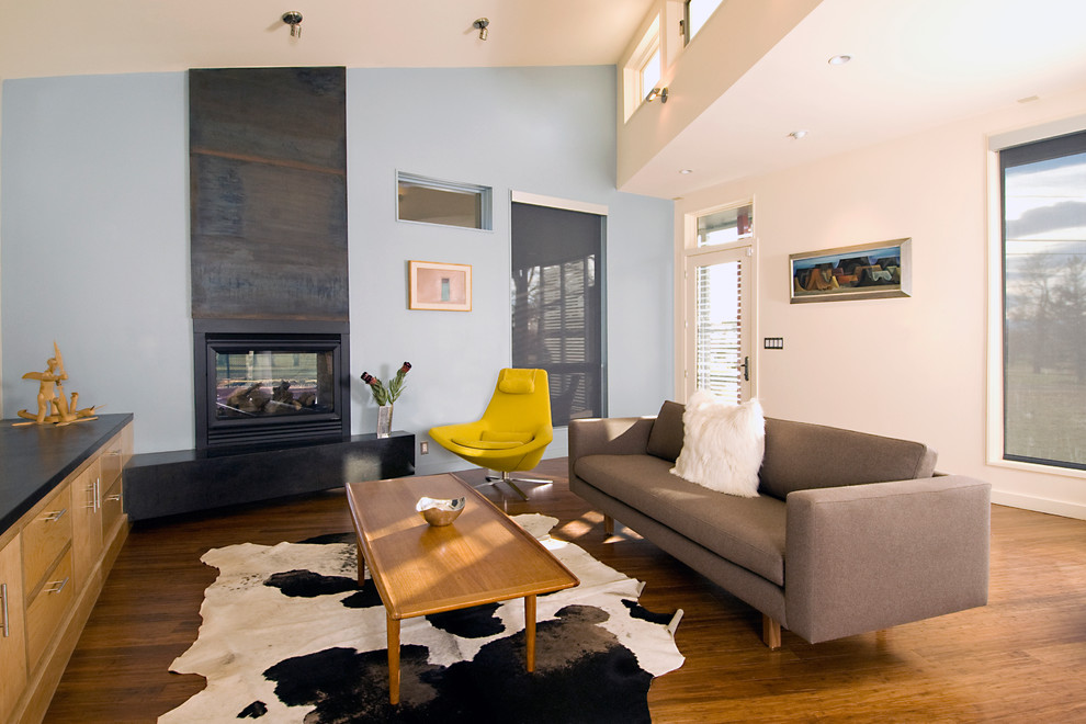 This is an example of a contemporary family room in Denver with grey walls, medium hardwood floors and a two-sided fireplace.