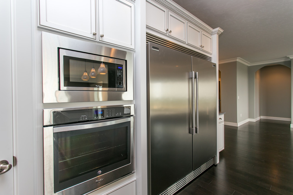 Inspiration for a mid-sized transitional l-shaped dark wood floor open concept kitchen remodel in Seattle with an undermount sink, shaker cabinets, white cabinets, quartz countertops, gray backsplash, glass tile backsplash, stainless steel appliances and an island