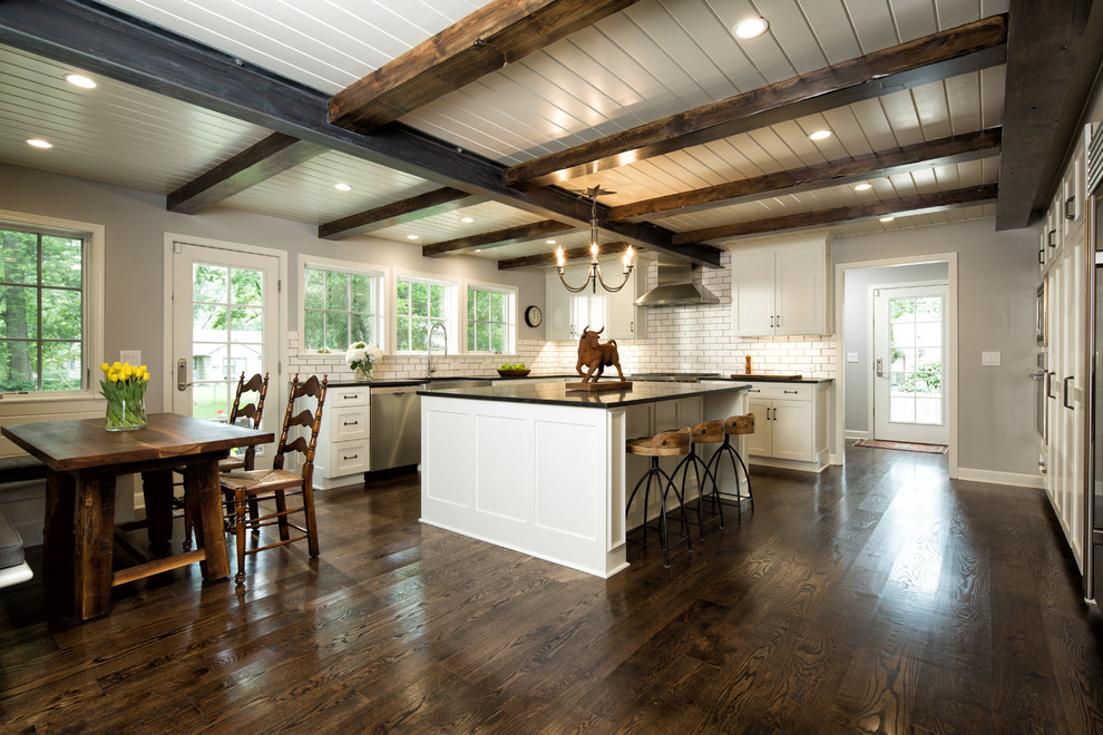 Inspiration for a mid-sized eclectic eat-in kitchen in Other with a farmhouse sink, shaker cabinets, white cabinets, granite benchtops, white splashback, subway tile splashback, stainless steel appliances, dark hardwood floors and with island.