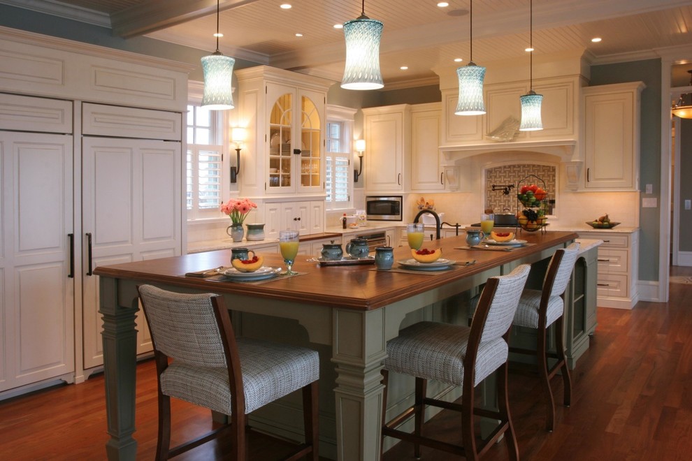 Traditional kitchen in Philadelphia with raised-panel cabinets, white cabinets, panelled appliances and wood benchtops.