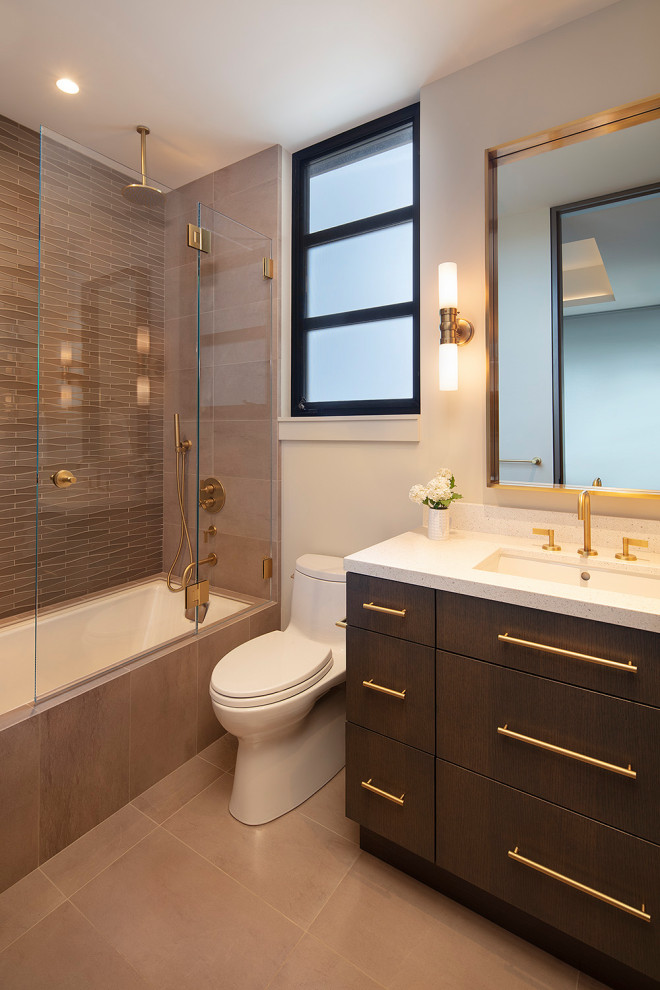 Пример оригинального дизайна: маленькая ванная комната в стиле модернизм с плоскими фасадами, полновстраиваемой ванной, душем над ванной, унитазом-моноблоком, бежевой плиткой, стеклянной плиткой, бежевыми стенами, полом из керамогранита, врезной раковиной, столешницей из искусственного кварца, бежевым полом, душем с распашными дверями, белой столешницей, тумбой под одну раковину, встроенной тумбой и темными деревянными фасадами для на участке и в саду