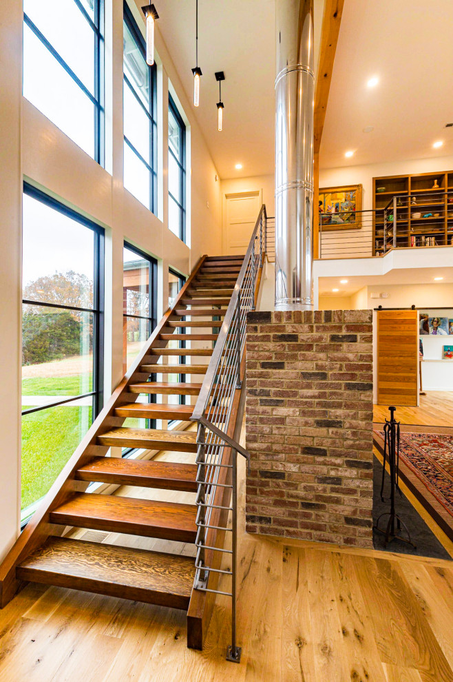 Ejemplo de escalera recta moderna de tamaño medio sin contrahuella con escalones de madera y barandilla de metal