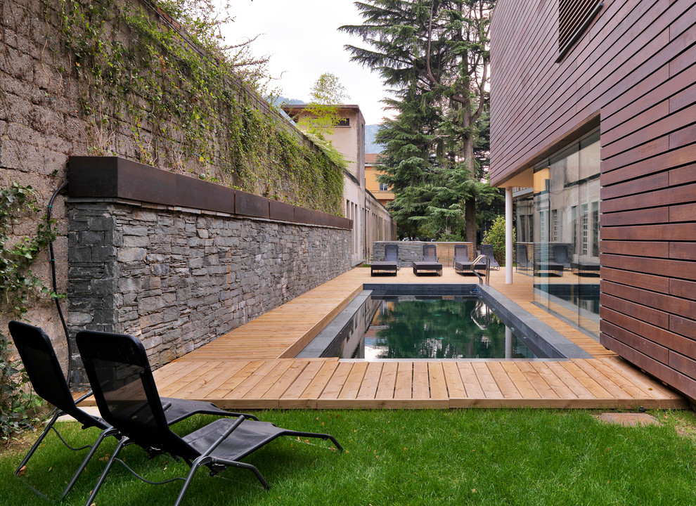 This is an example of a contemporary side yard rectangular lap pool in Turin with decking.