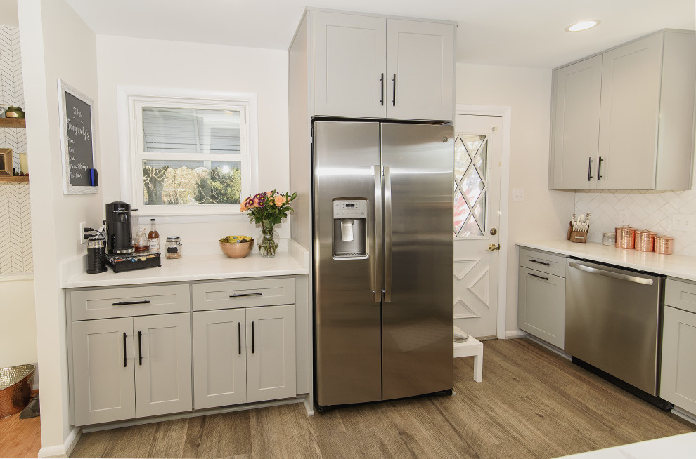 Small transitional u-shaped eat-in kitchen in Baltimore with an undermount sink, shaker cabinets, grey cabinets, quartz benchtops, white splashback, subway tile splashback, stainless steel appliances, vinyl floors, no island, brown floor and white benchtop.