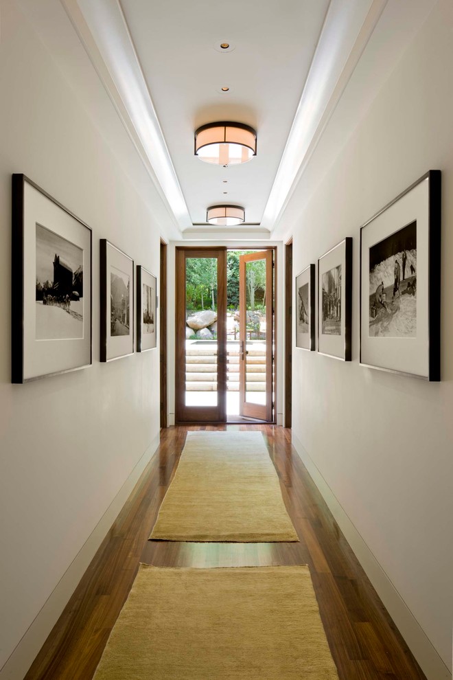 Transitional hallway in Denver with white walls and dark hardwood floors.