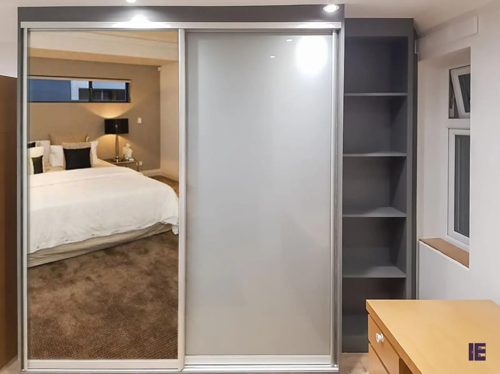 Immagine di un piccolo armadio o armadio a muro minimal con ante lisce, ante grigie, pavimento in compensato e pavimento marrone