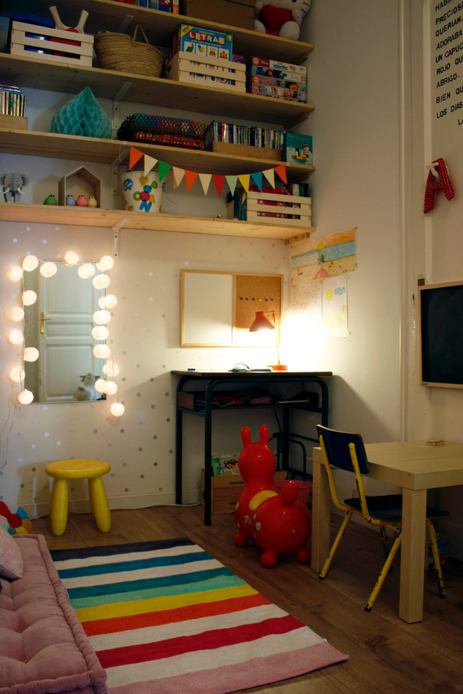 Photo of a mid-sized industrial gender-neutral kids' room in Barcelona with white walls and medium hardwood floors.