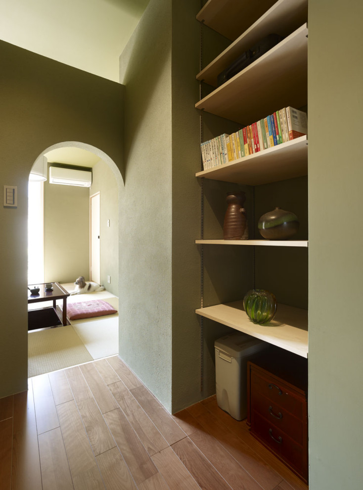 Design ideas for a mid-sized home office in Yokohama with green walls, plywood floors, brown floor and wallpaper.