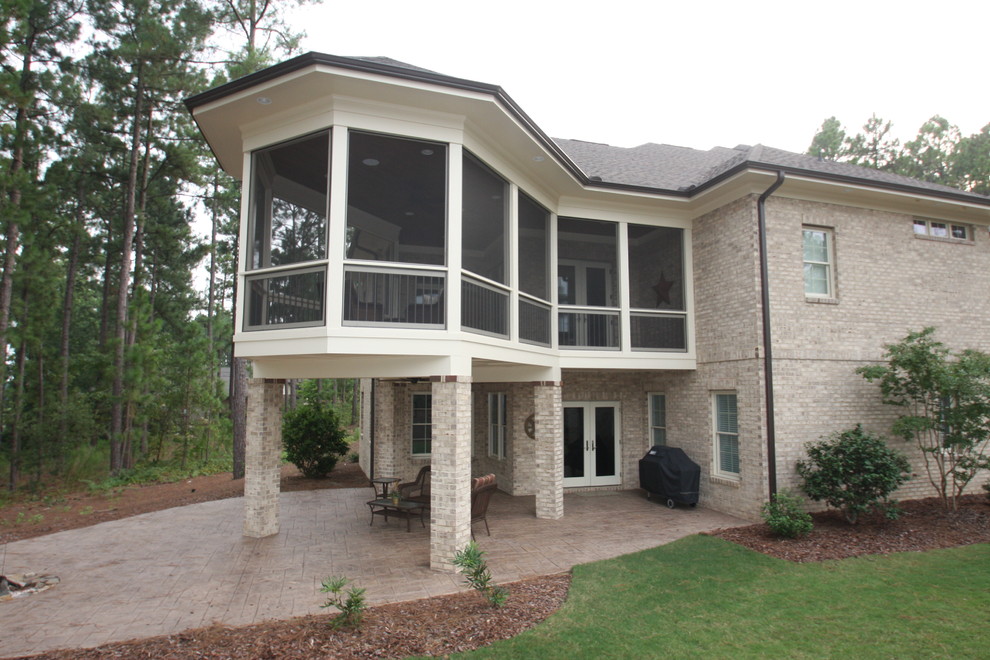 Photo of a large traditional backyard screened-in verandah in Raleigh with stamped concrete and a roof extension.