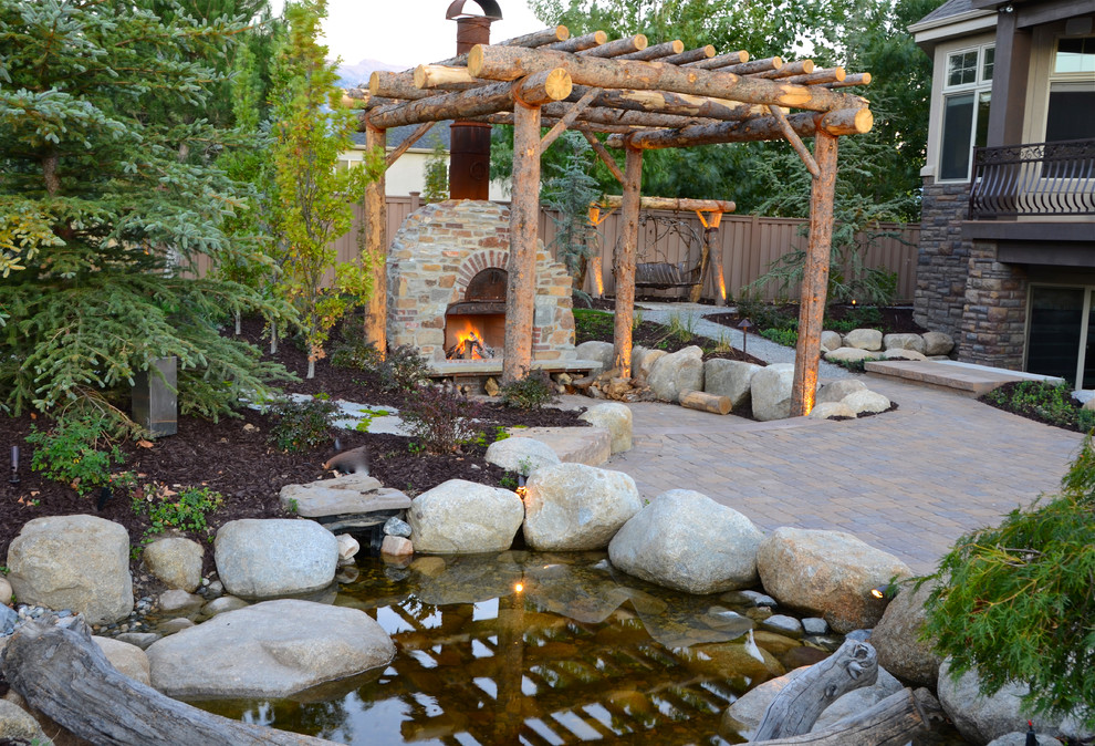 Large traditional backyard patio in Salt Lake City with a water feature and concrete pavers.
