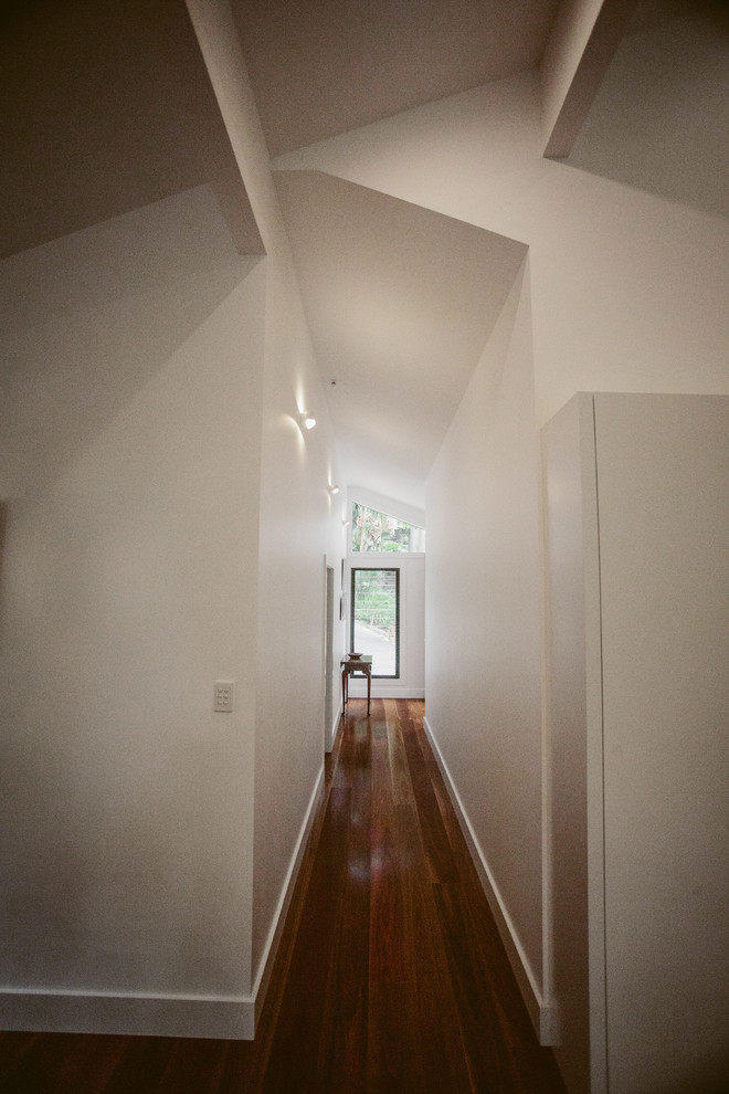 This is an example of a modern hallway in Sydney with white walls and dark hardwood floors.
