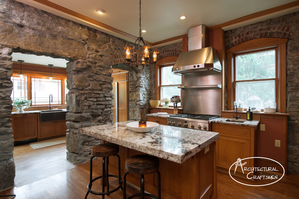 Country kitchen in Kansas City with a farmhouse sink, shaker cabinets, medium wood cabinets, granite benchtops and panelled appliances.