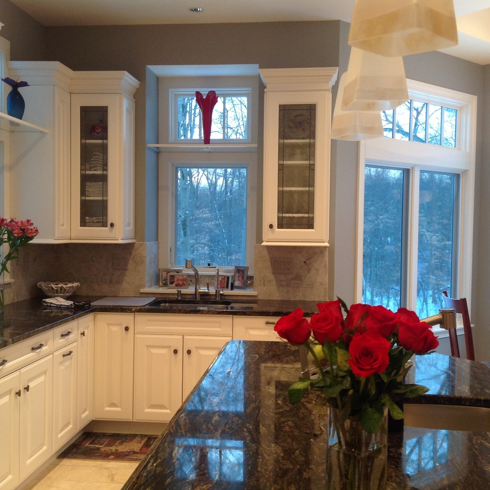 Eat-in kitchen - mid-sized transitional u-shaped travertine floor eat-in kitchen idea in New York with an undermount sink, raised-panel cabinets, white cabinets, granite countertops, beige backsplash, stone tile backsplash, stainless steel appliances and an island