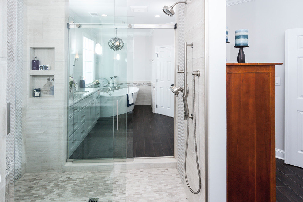 Inspiration for a large transitional master bathroom in DC Metro with recessed-panel cabinets, grey cabinets, a freestanding tub, a two-piece toilet, beige tile, marble, grey walls, porcelain floors, an undermount sink, granite benchtops and a double shower.