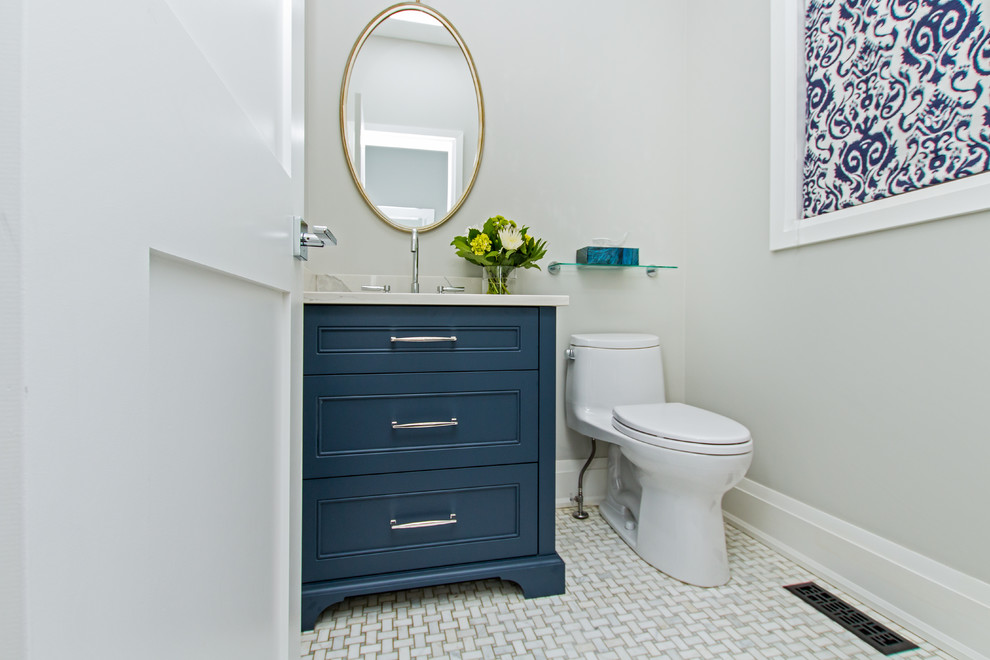 This is an example of a mid-sized traditional powder room in Toronto with recessed-panel cabinets, blue cabinets, a one-piece toilet, grey walls, marble floors, an undermount sink, marble benchtops, grey floor and white benchtops.