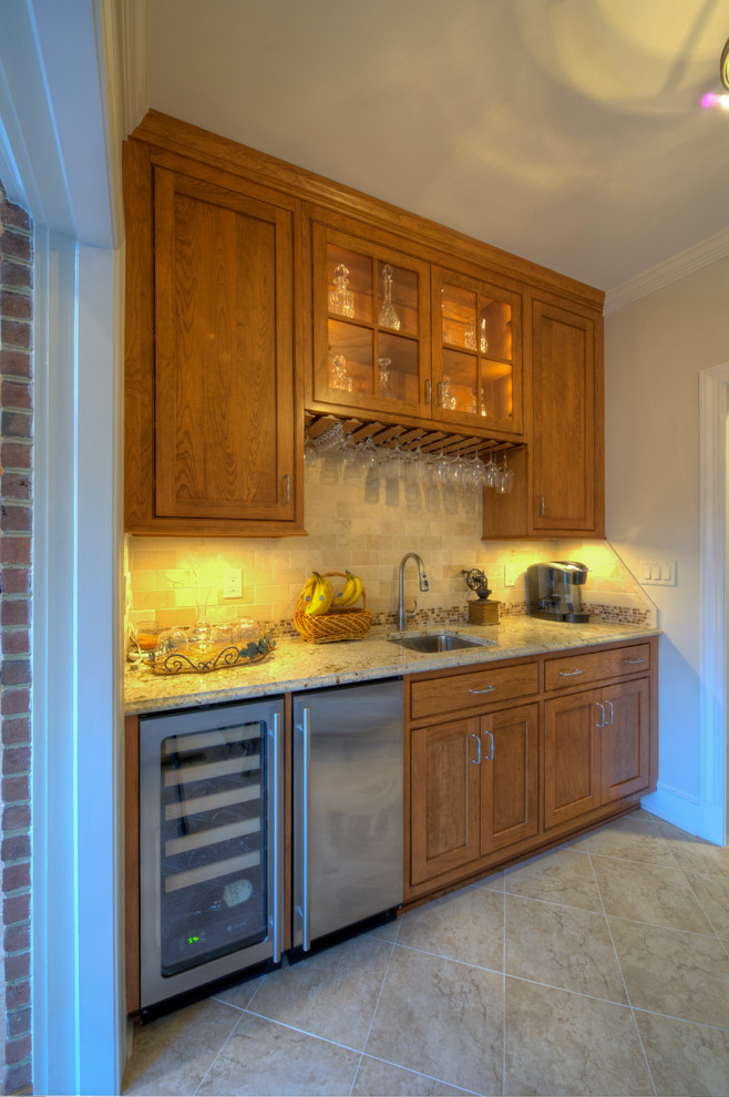 Photo of a small traditional single-wall wet bar in DC Metro with an undermount sink, shaker cabinets, medium wood cabinets, granite benchtops, beige splashback, subway tile splashback and ceramic floors.