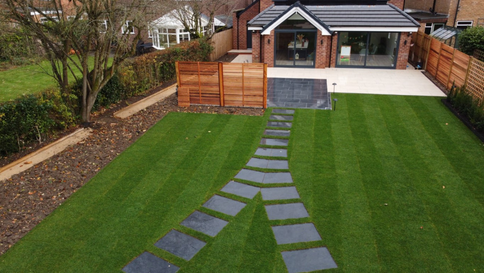 Esempio di un grande giardino moderno esposto in pieno sole dietro casa in estate con pavimentazioni in pietra naturale e recinzione in legno