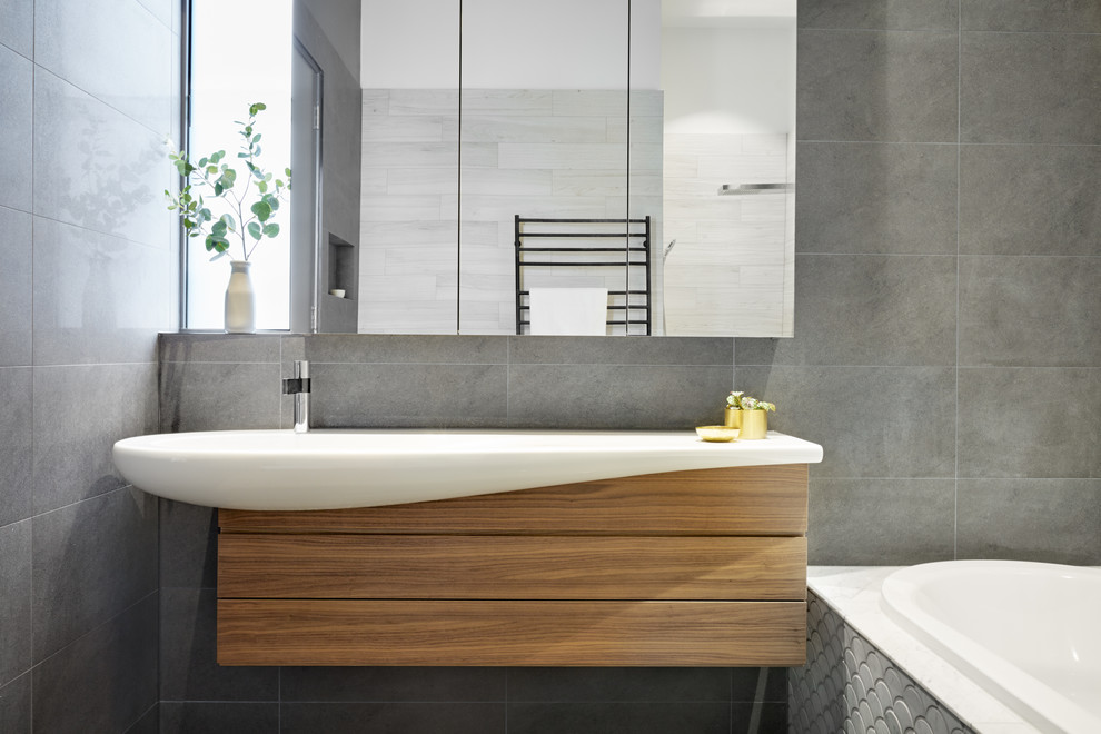Design ideas for a mid-sized contemporary master bathroom in Melbourne with glass-front cabinets, medium wood cabinets, a corner tub, an open shower, pebble tile, a vessel sink and laminate benchtops.