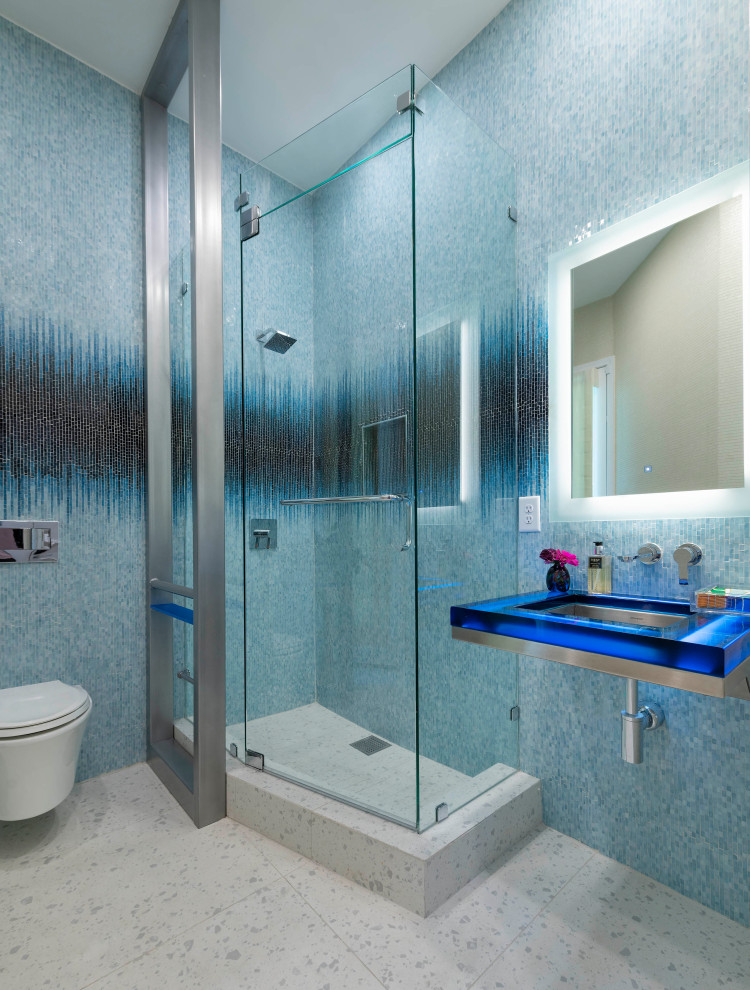 Aménagement d'une salle de bain moderne de taille moyenne avec des portes de placard bleues, une douche d'angle, WC à poser, un carrelage bleu, mosaïque, un mur bleu, un sol en carrelage de porcelaine, un lavabo encastré, un plan de toilette en stratifié, un sol beige, une cabine de douche à porte battante, un plan de toilette bleu, meuble simple vasque et meuble-lavabo suspendu.