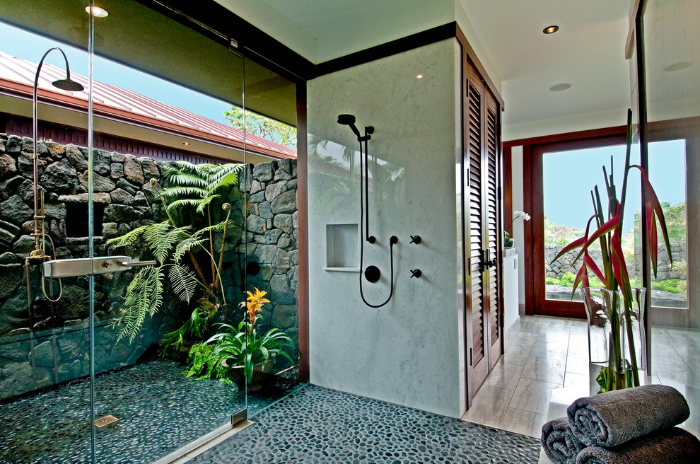This is an example of a tropical bathroom in Hawaii with gray tile, pebble tile floors and a curbless shower.