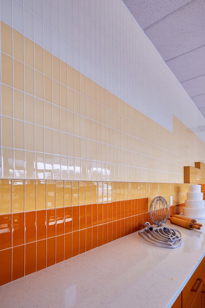 Idéer för att renovera ett stort funkis linjärt kök med öppen planlösning, med en nedsänkt diskho, orange skåp, gult stänkskydd, stänkskydd i glaskakel och rostfria vitvaror