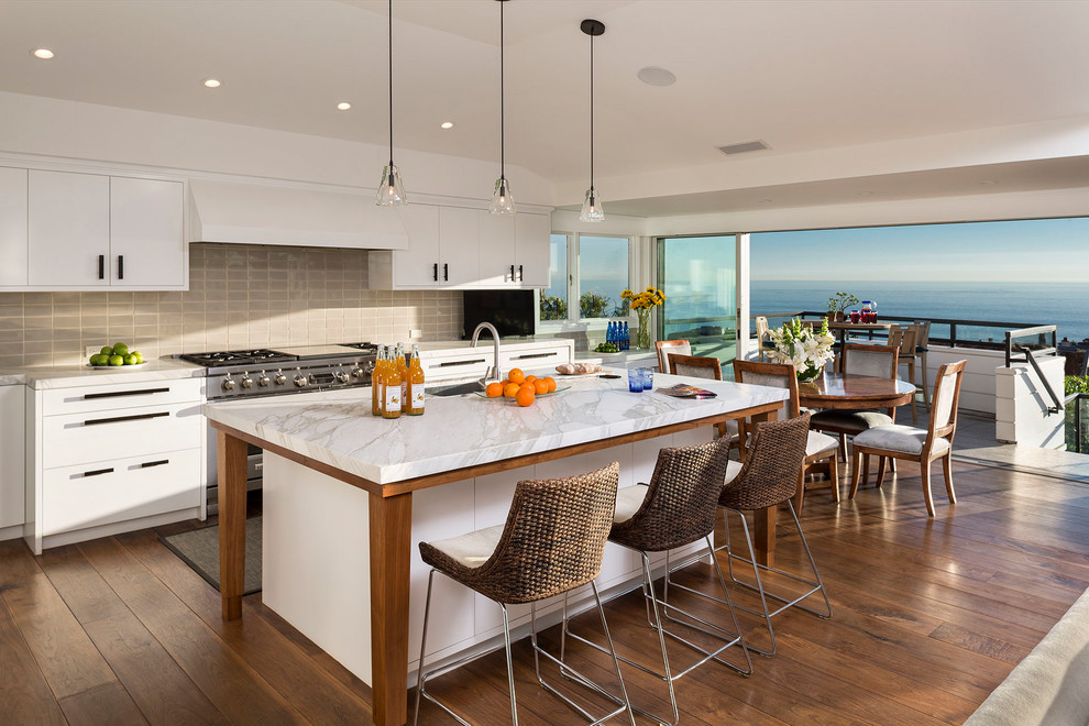 Inspiration for a contemporary galley eat-in kitchen in Boise with an undermount sink, flat-panel cabinets, white cabinets, grey splashback, subway tile splashback, stainless steel appliances, medium hardwood floors, with island, brown floor and white benchtop.