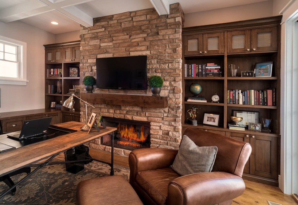 This is an example of a large transitional study room in Denver with beige walls, light hardwood floors, a standard fireplace, a brick fireplace surround, a freestanding desk and brown floor.