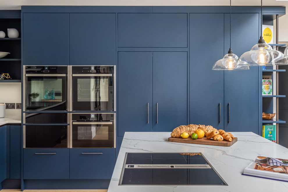 Esempio di un cucina con isola centrale minimal con ante lisce, ante blu e top bianco
