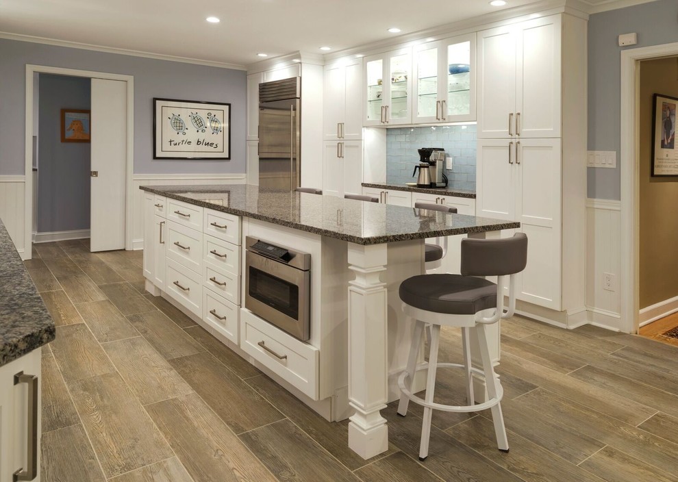 Mid-sized transitional u-shaped porcelain tile eat-in kitchen photo in Orange County with an undermount sink, shaker cabinets, white cabinets, granite countertops, blue backsplash, glass tile backsplash, stainless steel appliances and an island