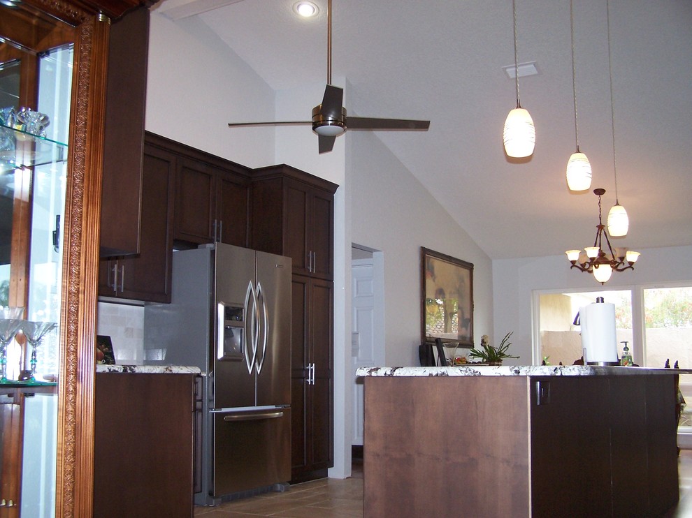 Example of a transitional eat-in kitchen design in Tampa with dark wood cabinets, granite countertops, white backsplash, ceramic backsplash and stainless steel appliances