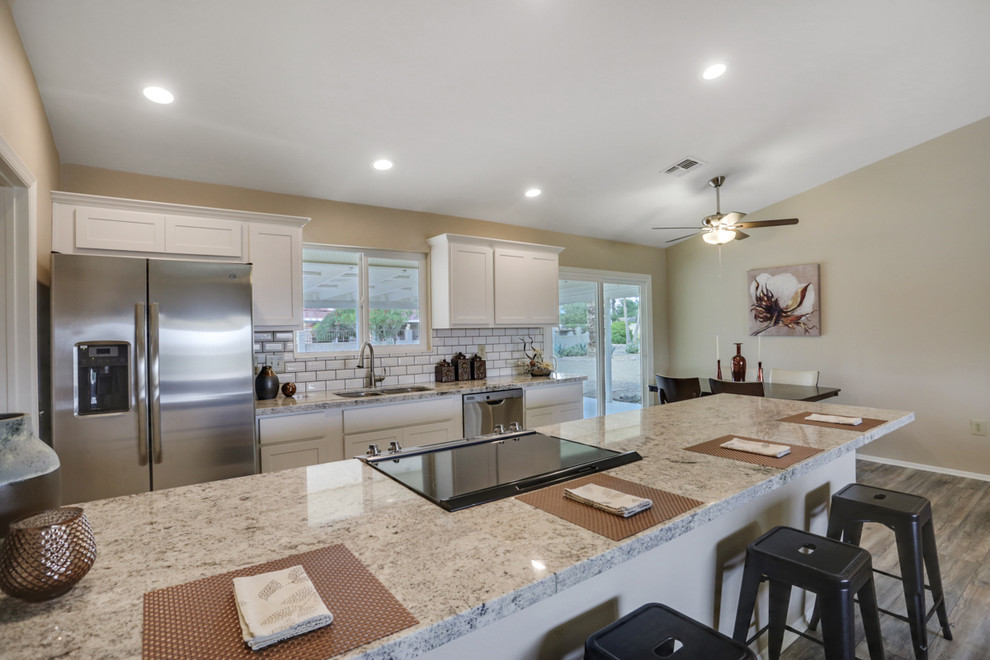 Open concept kitchen - small transitional single-wall laminate floor and beige floor open concept kitchen idea in Phoenix with an undermount sink, shaker cabinets, white cabinets, granite countertops, white backsplash, subway tile backsplash, stainless steel appliances, a peninsula and gray countertops