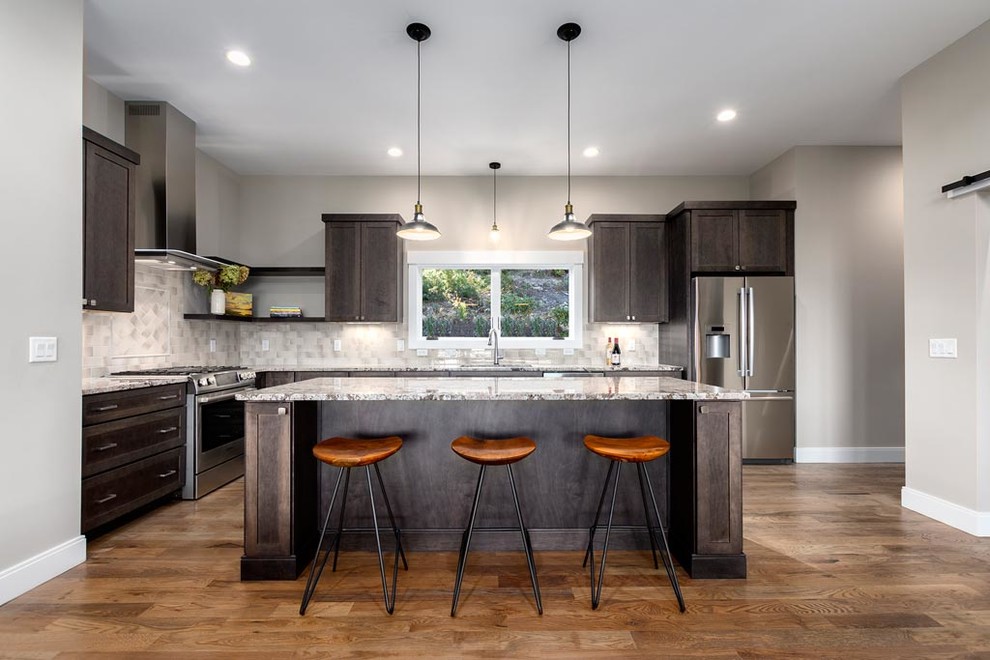 Mid-sized mountain style l-shaped light wood floor eat-in kitchen photo with an undermount sink, recessed-panel cabinets, dark wood cabinets, granite countertops, gray backsplash, ceramic backsplash, stainless steel appliances and an island