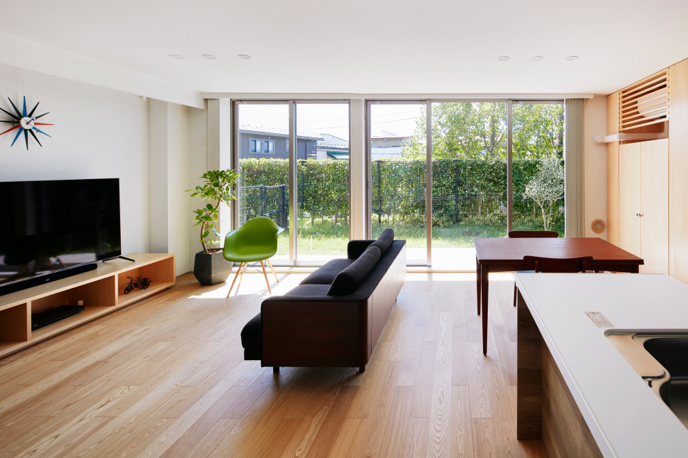 Bild på ett mellanstort allrum med öppen planlösning, med ett finrum, vita väggar, en fristående TV, plywoodgolv och beiget golv