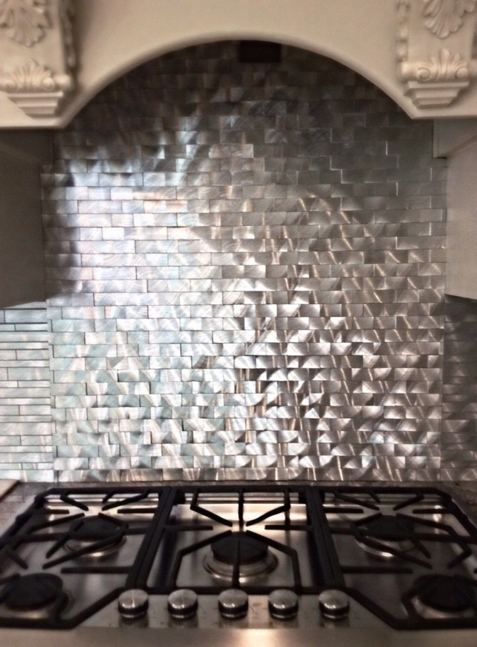 Eat-in kitchen - mid-sized transitional l-shaped travertine floor eat-in kitchen idea in Houston with a farmhouse sink, raised-panel cabinets, white cabinets, granite countertops, metallic backsplash, metal backsplash, stainless steel appliances and an island