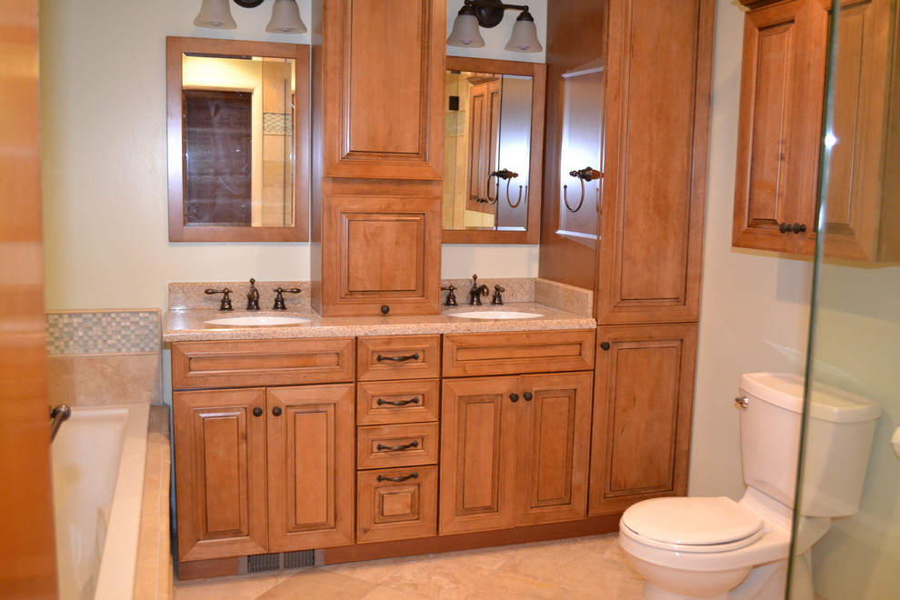 Inspiration for a mid-sized arts and crafts master bathroom in Columbus with stone tile, recessed-panel cabinets, medium wood cabinets, a corner shower, a two-piece toilet, beige tile, beige walls, ceramic floors, a drop-in sink and granite benchtops.