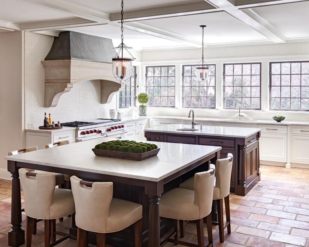 Photo of a large traditional u-shaped eat-in kitchen in Charlotte with a single-bowl sink, shaker cabinets, white cabinets, marble benchtops, white splashback, matchstick tile splashback, stainless steel appliances, terra-cotta floors, multiple islands and beige floor.