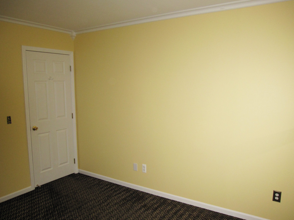 Imagen de habitación de invitados tradicional de tamaño medio sin chimenea con paredes amarillas, moqueta y suelo negro