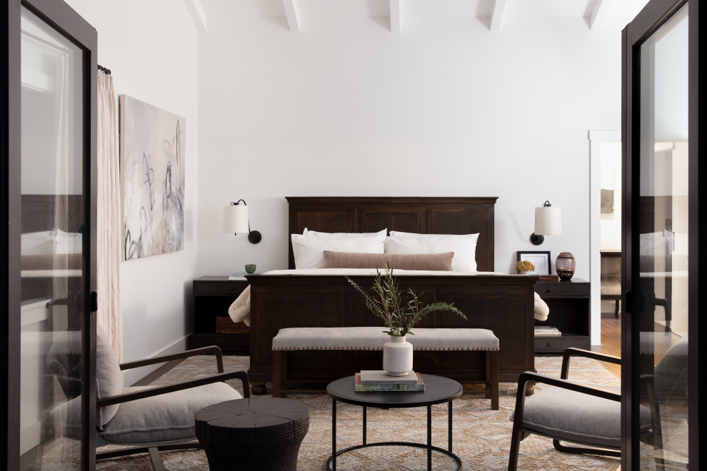 Großes Landhaus Hauptschlafzimmer mit weißer Wandfarbe, dunklem Holzboden, braunem Boden und freigelegten Dachbalken in Santa Barbara