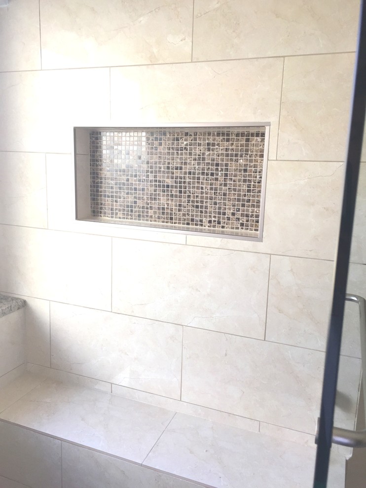 Photo of a large traditional master bathroom in Dallas with an alcove shower, beige tile, raised-panel cabinets, white cabinets, a freestanding tub, a one-piece toilet, ceramic tile, beige walls, porcelain floors, a drop-in sink and tile benchtops.